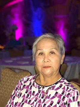 A cheerful older woman enjoys the vibrant atmosphere of a gathering filled with colorful lights.