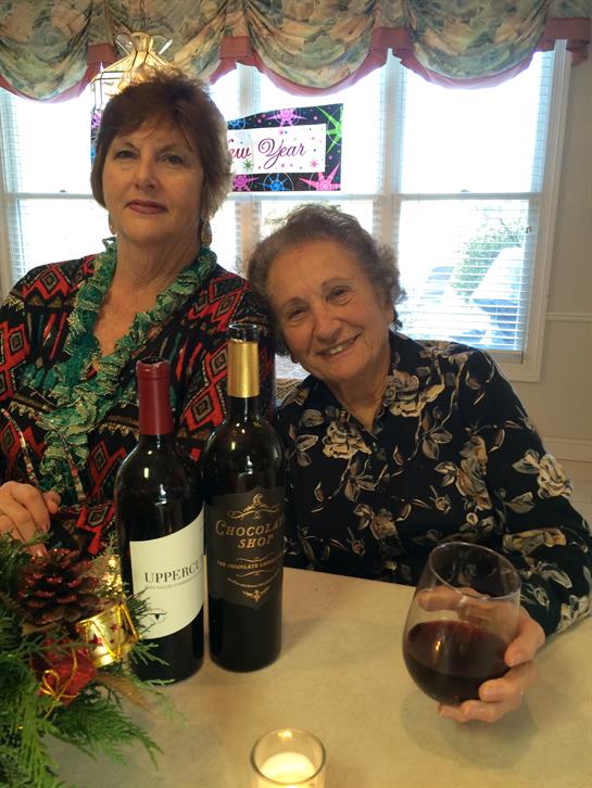 Two friends share a delightful evening with wine, smiles, and festive attire at home.