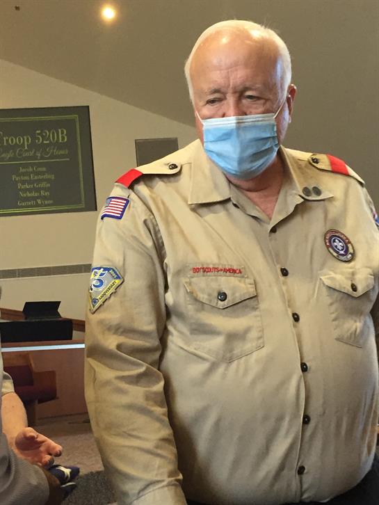 An elderly leader assists youth volunteers during a community service event wearing masks.
