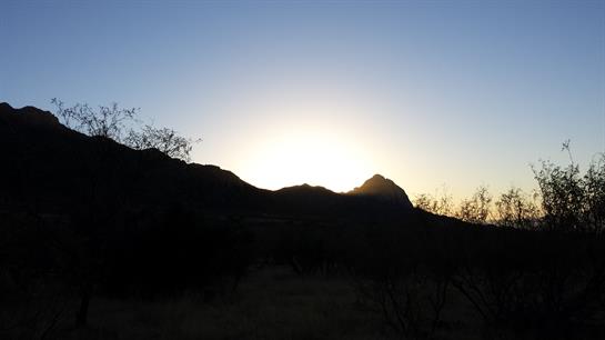 A serene sunset paints the sky above a mountain range with hues of orange and blue.