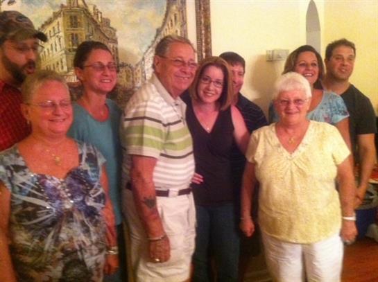 A joyful gathering of friends and family sharing smiles and laughter in a warm indoor atmosphere.