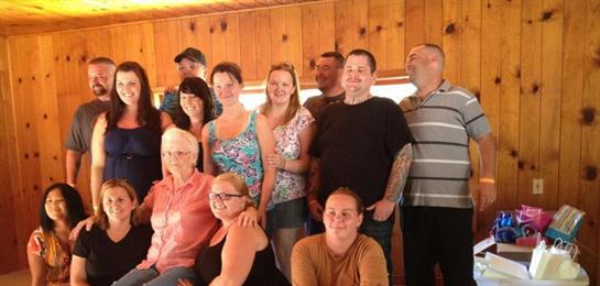Group of family members smiling and posing together inside a cozy lakeside cabin in summer.