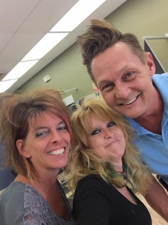 Three friends smile together in a vibrant salon, capturing a cheerful moment filled with laughter.