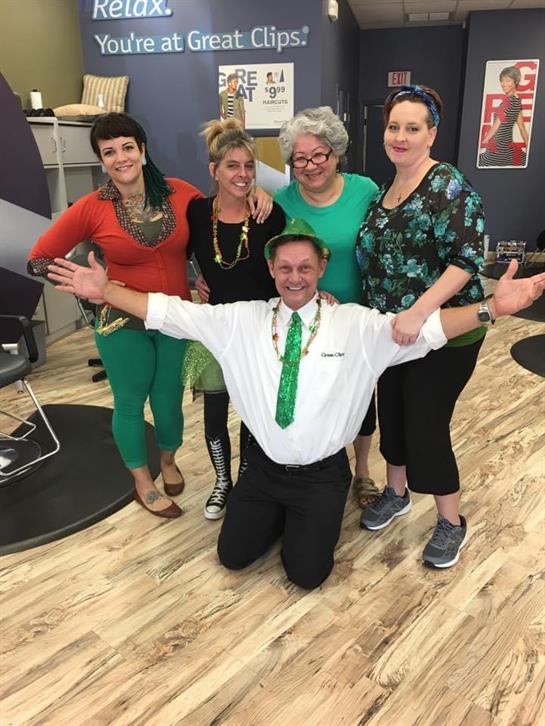 Friends wearing green outfits celebrate together in a cheerful gathering at a salon.