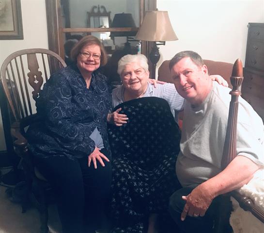 Three family members share smiles while sitting together in a warm, inviting living room.