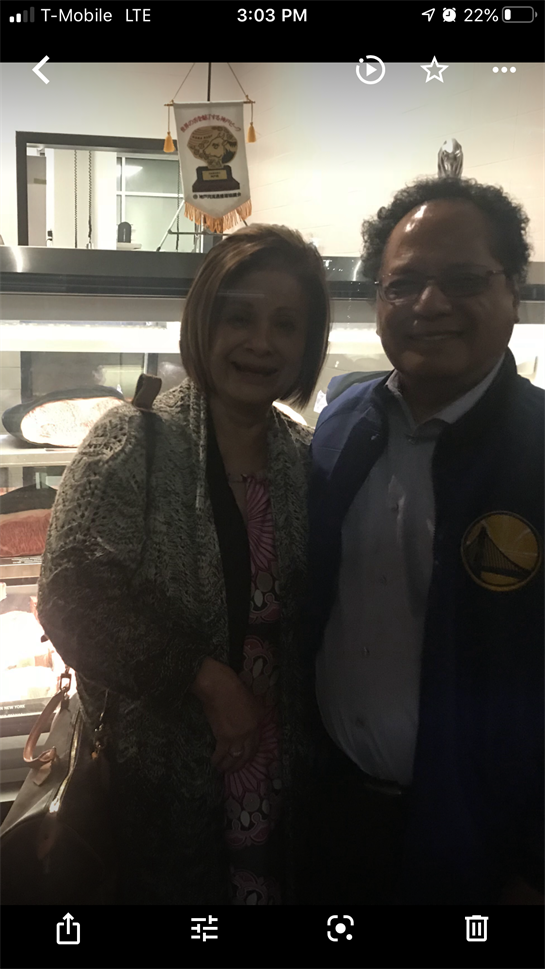 Friends pose happily together in a restaurant, surrounded by glass displays of food.