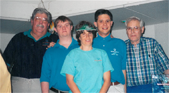 Group in matching blue shirts shares a joyful celebration together.