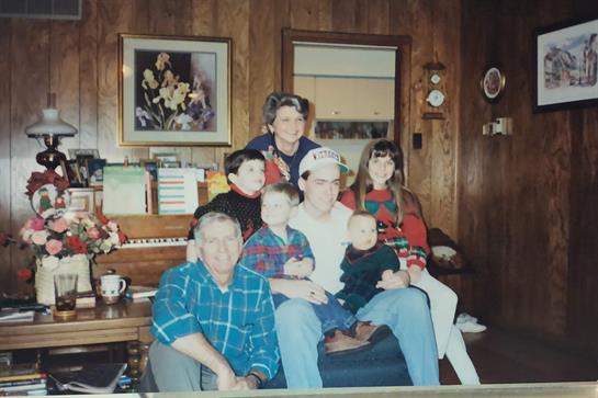 A family poses together in a warmly decorated living room, celebrating the holiday spirit.