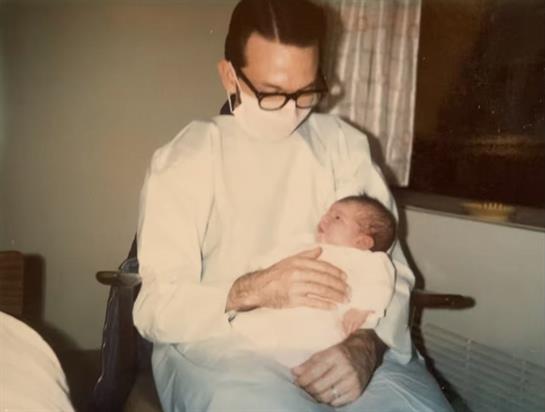 A father lovingly cradles his newborn child in a warm and intimate home atmosphere.