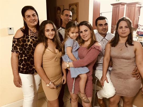 A joyful family and friends gather at home, celebrating with laughter and casual attire.