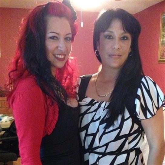Two smiling women in colorful outfits enjoy a lively atmosphere together.