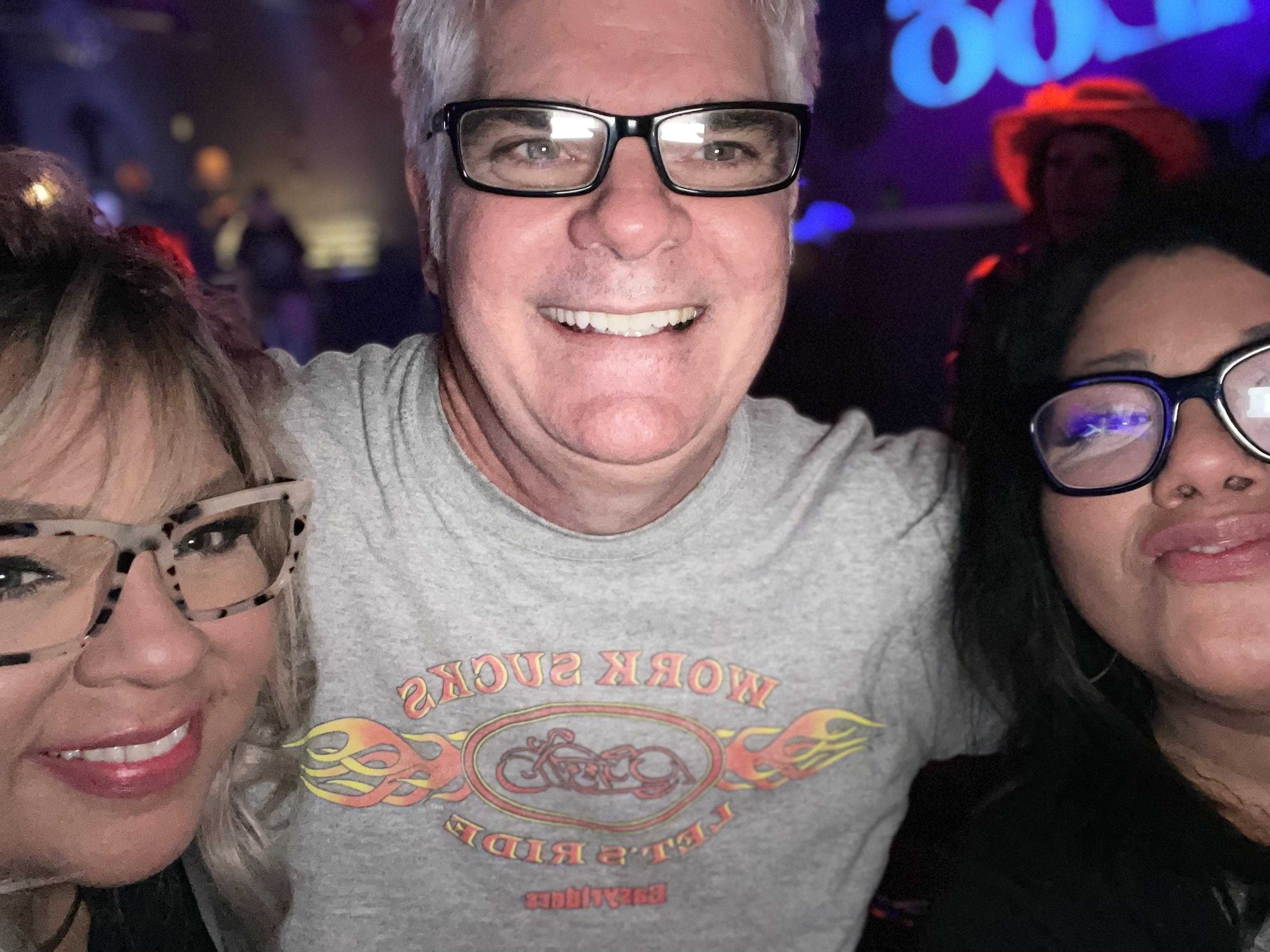 Three friends gather together, smiling and taking a selfie during an energetic night out.