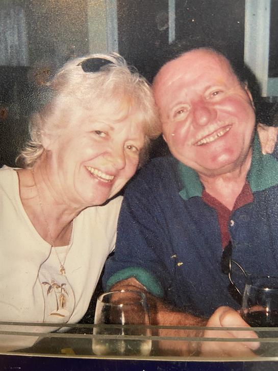 A joyful couple smiles and poses together while enjoying their drinks at a welcoming restaurant.
