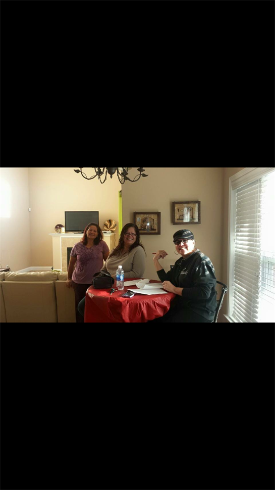 Three friends share laughter and conversation around a table in a warm living room during the day.