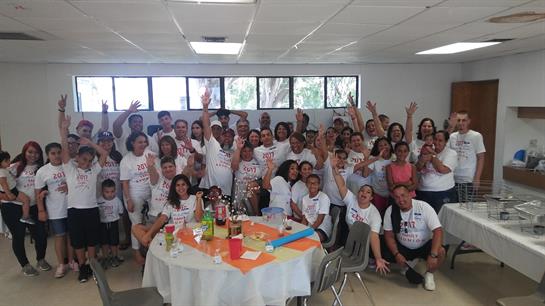 A joyful group poses together, hands raised in celebration amid festive decorations.