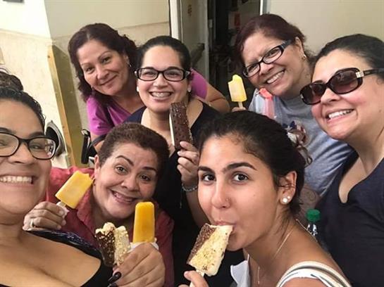 Friends smile and share colorful popsicles while enjoying a cheerful moment together outdoors.