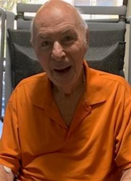 A joyful senior man wearing an orange shirt enjoys his time outdoors in a relaxed atmosphere.