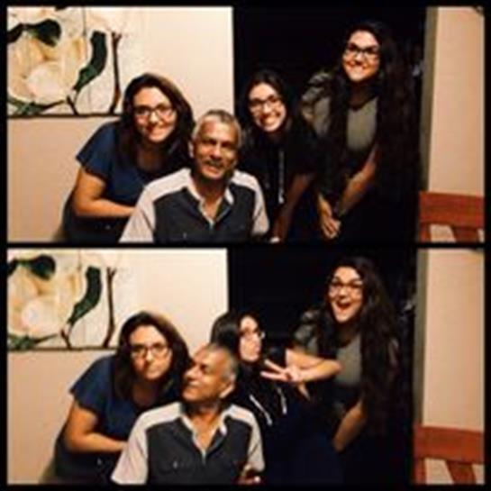Three women joyfully pose with a man, sharing smiles and happiness in their cozy home setting.