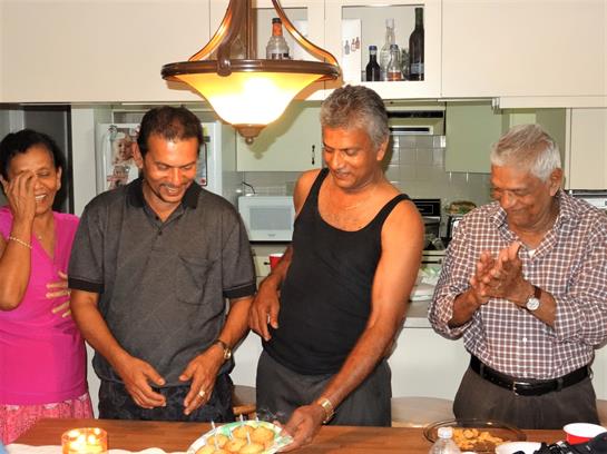 Four friends laugh around a table of homemade dishes, savoring the moment together.