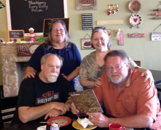 Four friends gather around a table, sharing food and happy moments in a delightful eatery.