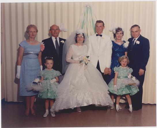 A wedding party stands together, showcasing elegant attire and joyful expressions at a celebration.