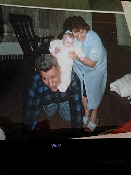 Grandparents interact joyfully with their grandchild in a comfortable living room.