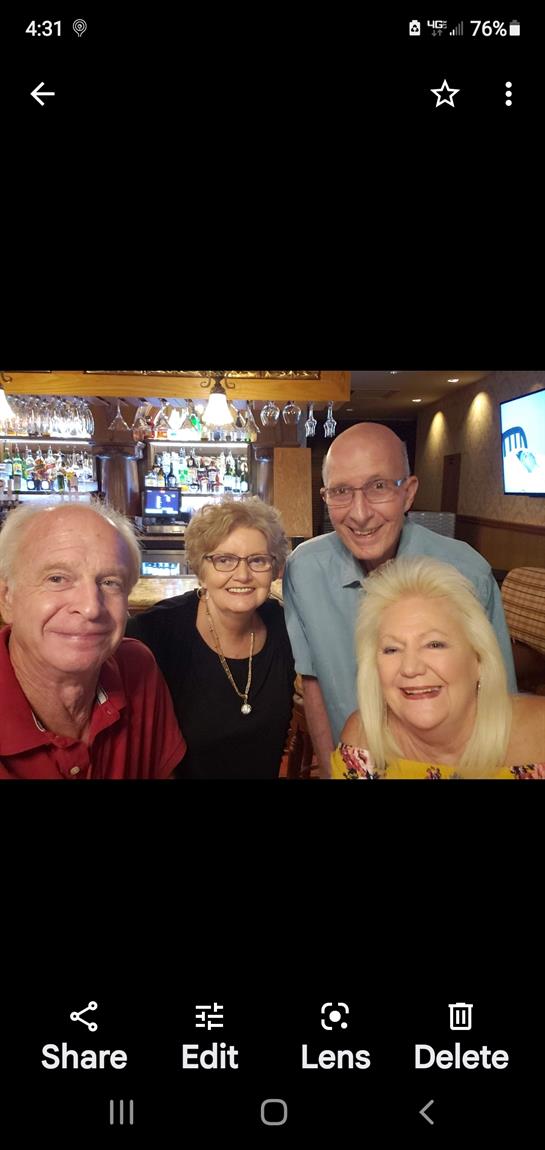 Four friends share joyful moments at a bar, celebrating together with drinks and smiles.
