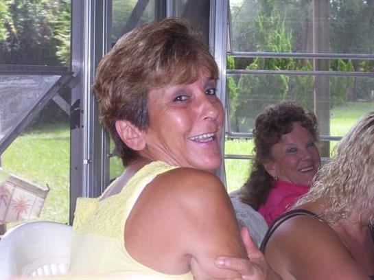 Two women share laughter and happiness during a cheerful gathering in a bright space.