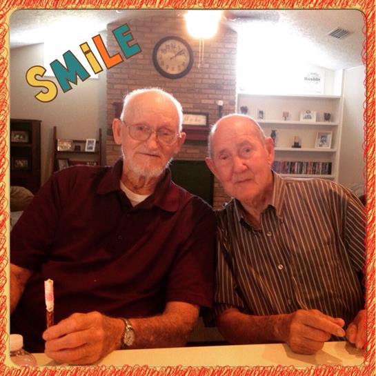 Two senior men are enjoying a crafting session at a cozy table, sharing smiles and laughter.