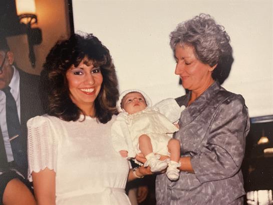 Two women share a tender moment holding a newborn in a warm indoor environment, radiating happiness.