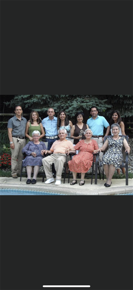 A large family enjoys quality time together, smiling and posing around a pool in a backyard.