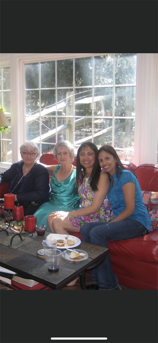 Four women enjoy a relaxing afternoon together in a bright living room filled with natural light.