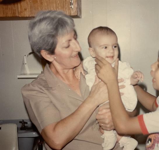 A grandmother shares a heartwarming moment with her smiling grandchild in a homey kitchen.