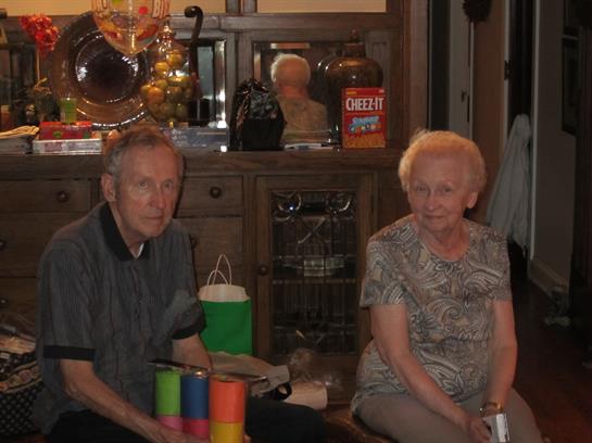 Older couple sits together in a cozy setting, sharing a quiet moment with colorful toys.