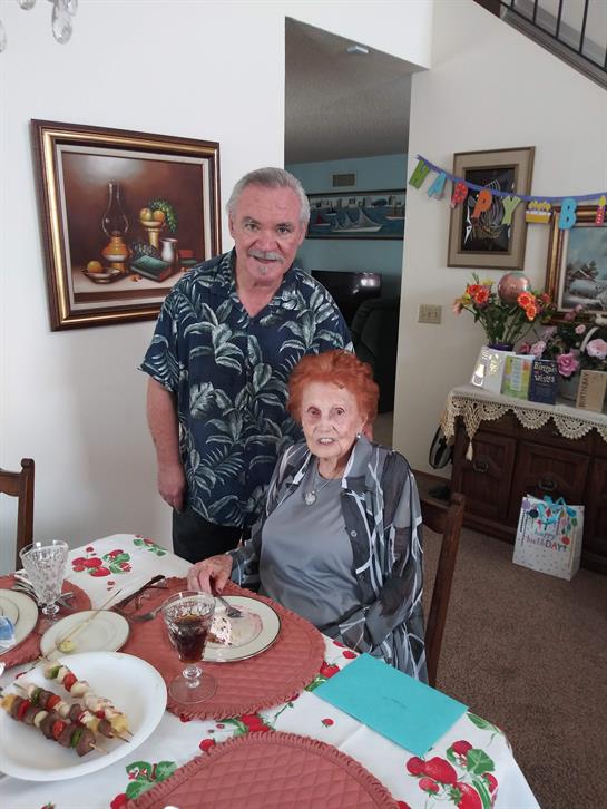 Two individuals enjoy a festive meal together in a warmly decorated living space.
