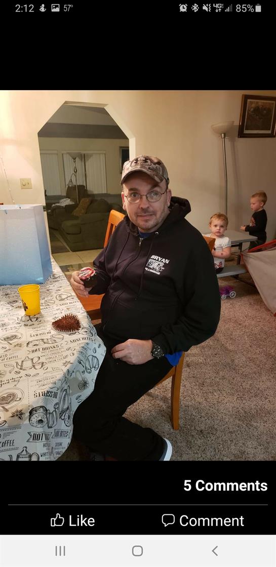 A man enjoys dessert at a table while kids play in the background, creating a warm atmosphere.