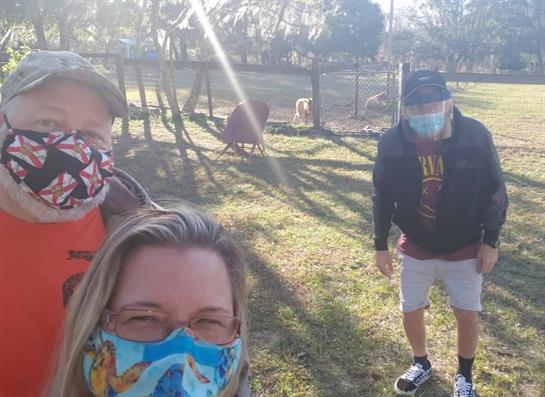 Friends enjoy a sunny day at the park, taking precautions with masks while smiling together.