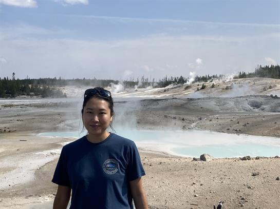 Person enjoying the unique geothermal landscape in Yellowstone National Park under clear skies.