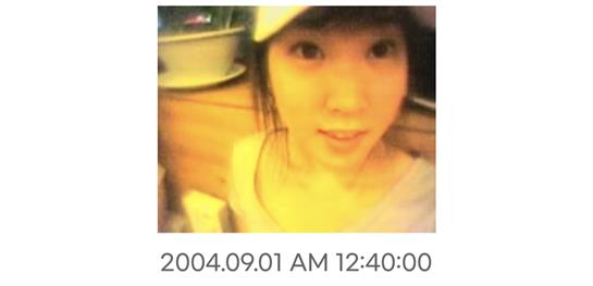 A young woman poses for a casual selfie while wearing a cap and smiling warmly indoors.