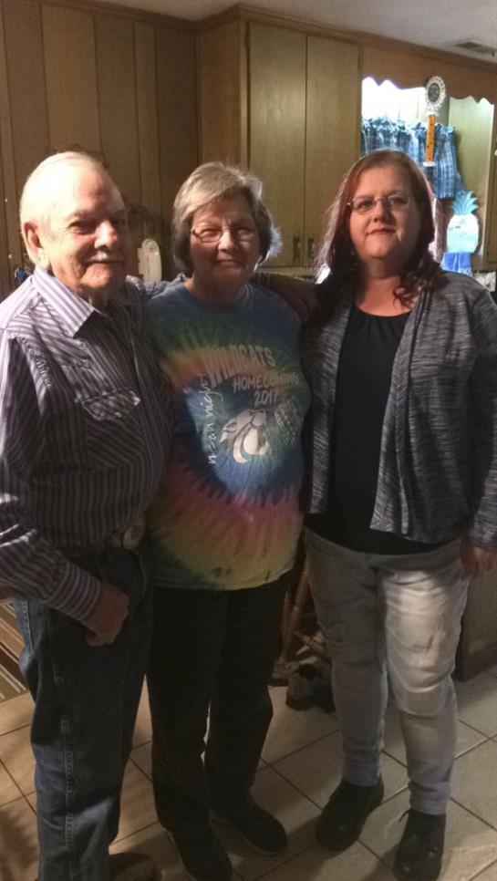 Three friends smiling together in a cozy indoor setting, sharing joyful moments at night.