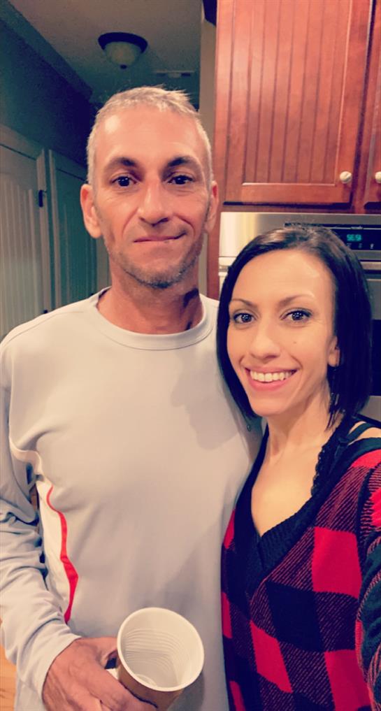 Couple stands close in their kitchen, smiling happily while enjoying each other's company.