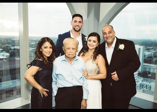 A family stands together, smiling warmly in a contemporary setting with a city view.