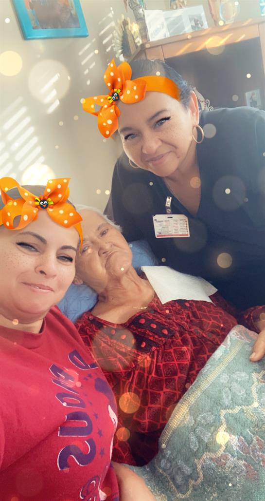 Two individuals smiling beside an elderly woman in a healthcare setting filled with warmth.