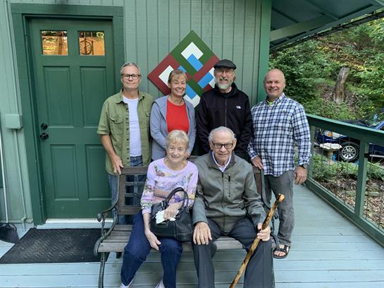 Friends and family pose happily together in front of a colorful cabin, enjoying quality time.