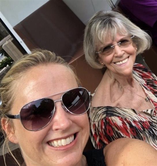 Two women pose playfully for a selfie, showcasing their friendship and joy in the sun.