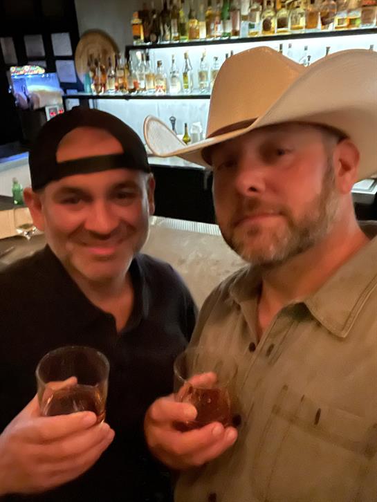 Two friends raise glasses in celebration at a bustling bar, creating lasting memories together.