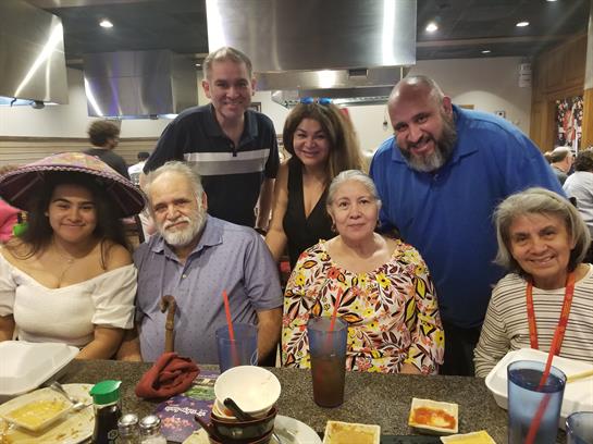 A group of friends and family members enjoy each other's company at a restaurant.