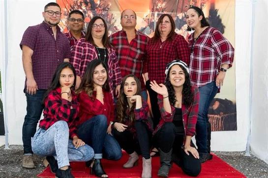 Friends in matching flannel shirts joyfully pose together for a holiday celebration.