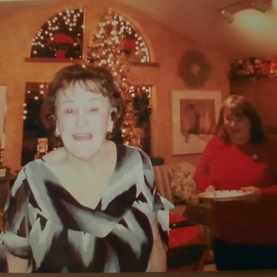 Two women celebrate together in a warmly decorated room during a holiday gathering.