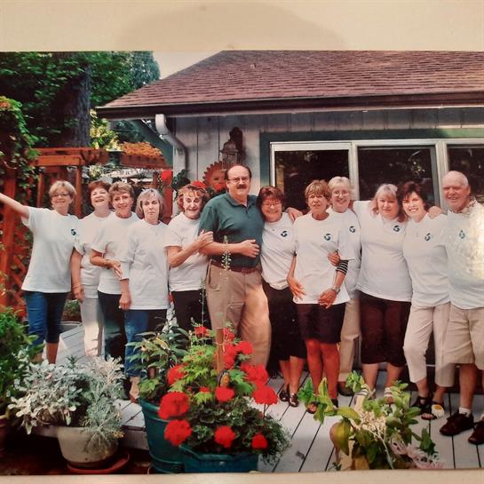 Friends enjoy a joyful summer gathering in a well-decorated backyard filled with flowers.